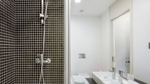 Un bany modern amb dutxa, un lavabo i un mirall.