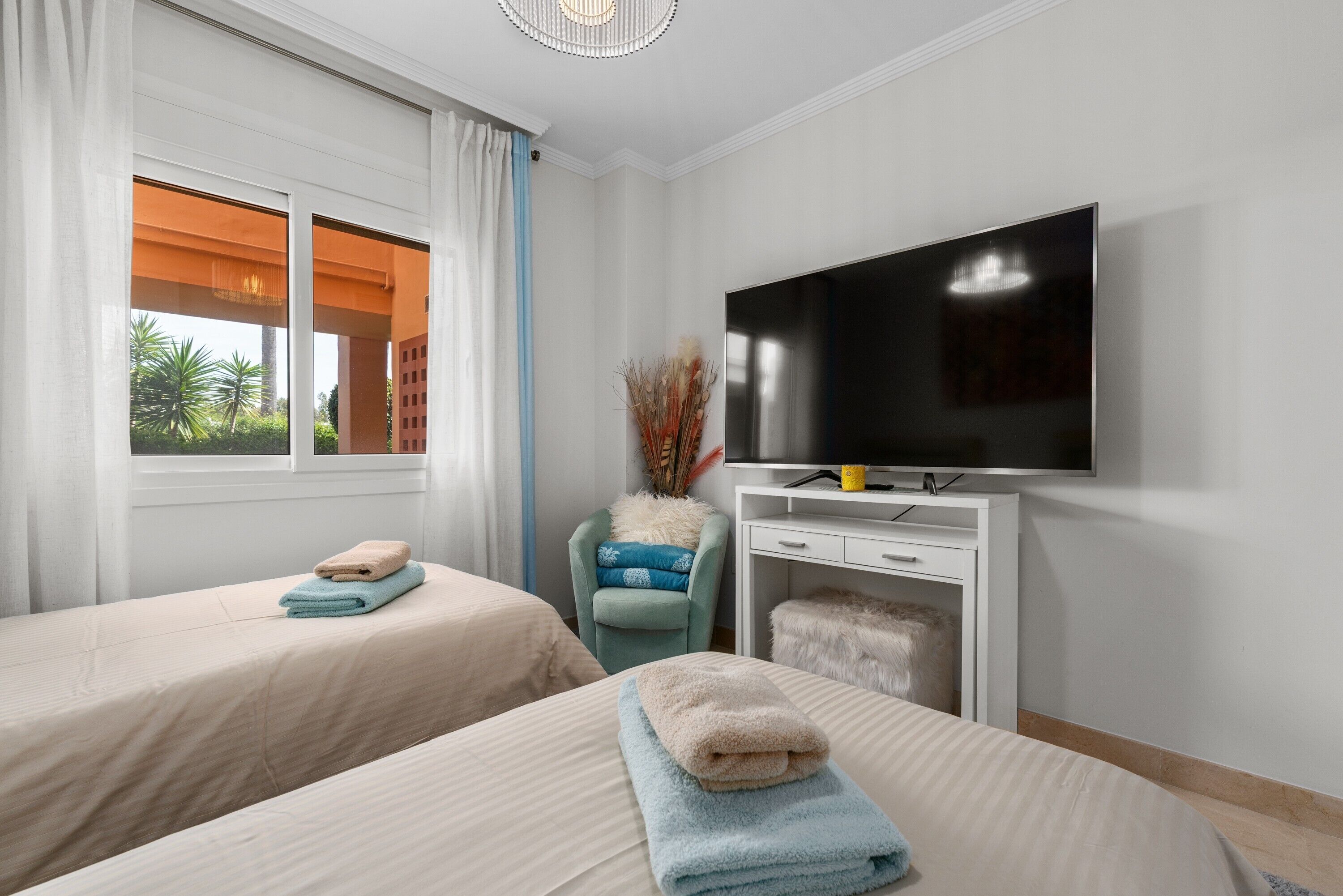 A hotel room with two beds, a TV, and a window with curtains.