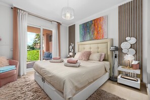 Ein modernes Schlafzimmer mit einem großen Bett, Blick ins Freie und einer dekorativen Wandgestaltung.