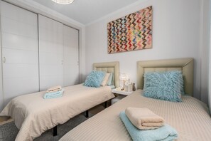 Une chambre d’hôtel avec deux lits, une armoire, une table de chevet et un tableau accroché au mur.