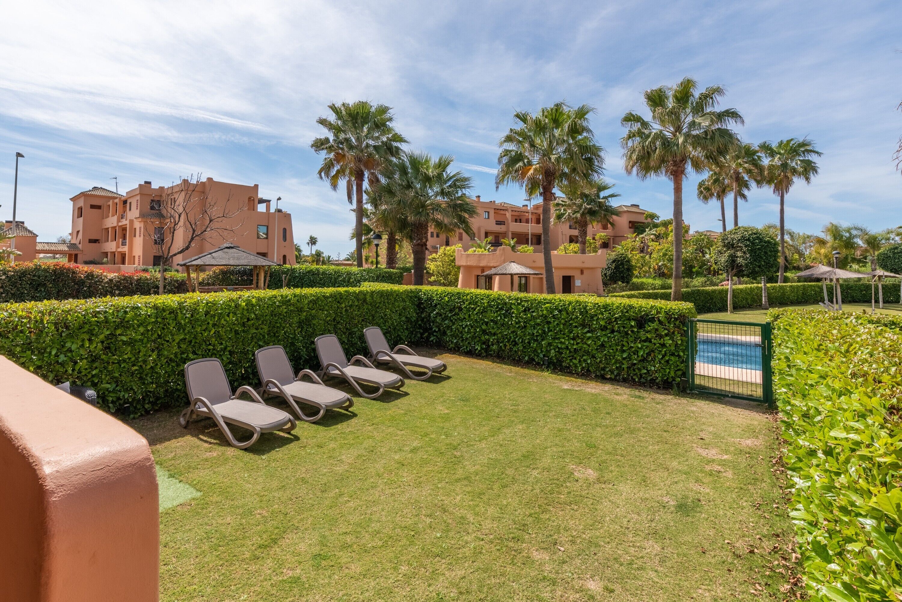 A poolside area with lounge chairs, a well-maintained lawn, and a clear view of the pool.