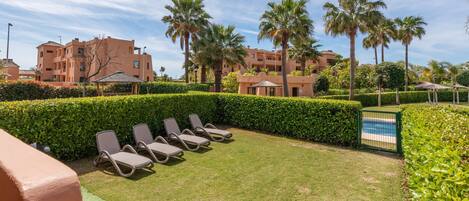 A poolside area with lounge chairs, a well-maintained lawn, and a clear view of the pool.