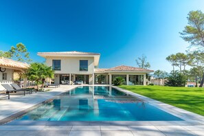 Una moderna casa a due piani con una piscina di fronte.