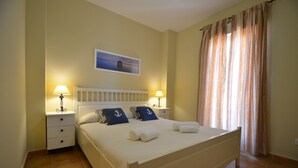 A neatly made bed with pillows, a bedside table with a lamp, and a painting on the wall. - Playa Grande 197 - Two Bedroom Apartment, Sleeps 5 (Punta del moral)