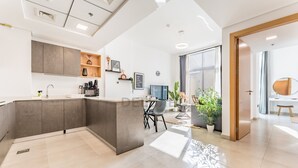 A modern kitchen with a central island, built-in cabinets, and a dining area with a table and chairs. - Balcony Offering Community Views 1BR w/AsstRm,Walking Distance to CommunityPark (Dubai)