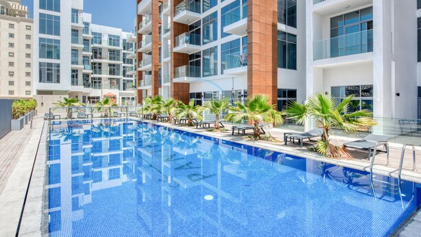 A modern hotel with a large pool, multiple balconies, and outdoor seating areas. - Balcony Offering Community Views 1BR w/AsstRm,Walking Distance to CommunityPark (Dubai)
