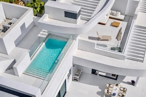 A modern building with a rooftop pool, outdoor seating, and a staircase.