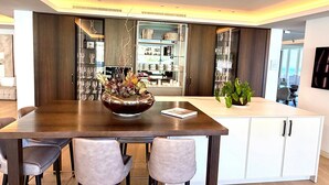 A modern dining area with a dark wooden table, white chairs, and a decorative centerpiece.
