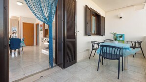 A dining area with a table and chairs, a sliding door, and a kitchen in the background. - Amor di Salento by BarbarHouse (San Foca)