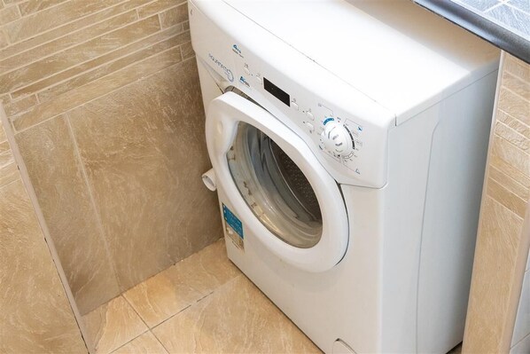 Een voorlader wasmachine in een badkamer met betegelde muren en vloer.