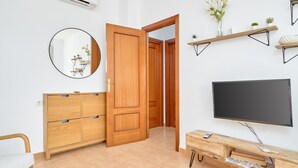 Ein Zimmer mit einem Holzschrank, einem runden Spiegel, einem Fernseher und einem Regal mit Blumen.