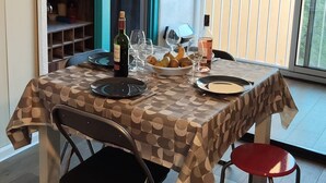 Un coin repas avec une table dressée pour deux personnes, un four à micro-ondes et une bouteille de vin.