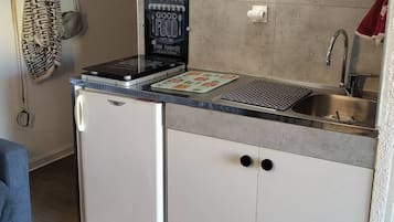 Een koelkast, een microgolfoven, een oven, kookgerei, borden en bestek