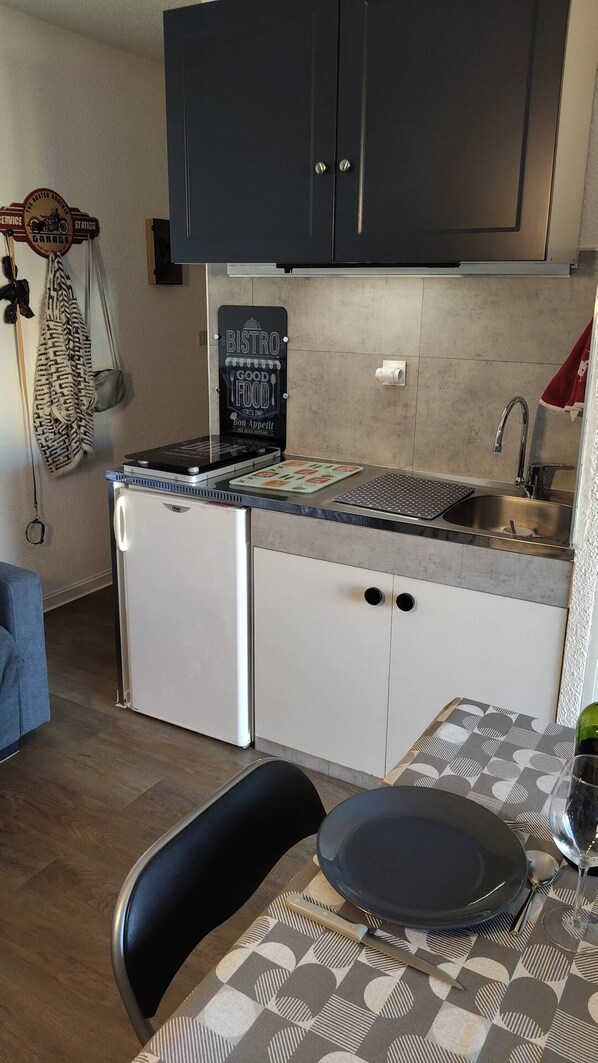 Een koelkast, een microgolfoven, een oven, kookgerei, borden en bestek