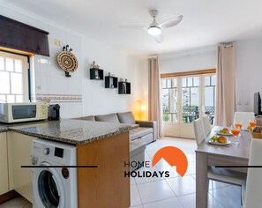 Una cocina moderna con microondas, lavadora y comedor con mesa lista para el desayuno.