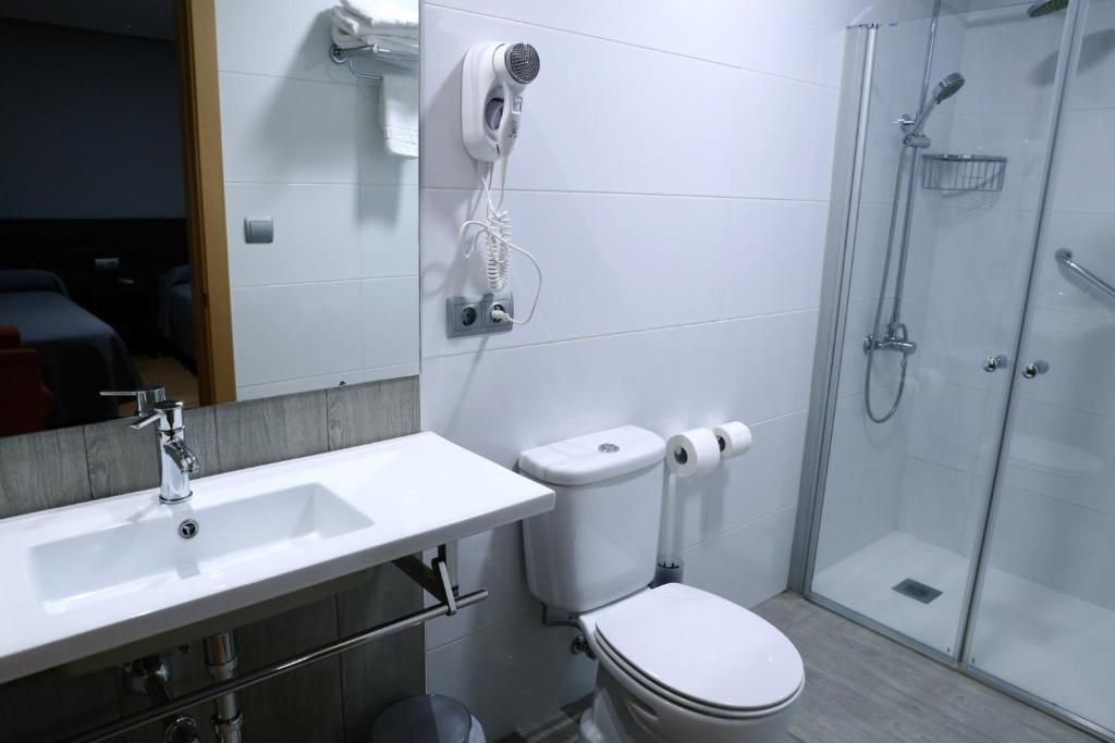 Un baño moderno con lavamanos, inodoro y ducha blancos.