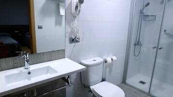 Un baño moderno con lavamanos, inodoro y ducha blancos.
