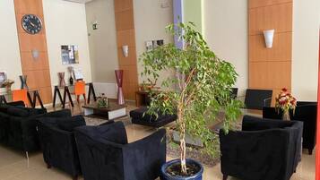 Un espace d’accueil avec une horloge, des sièges et une plante en pot.