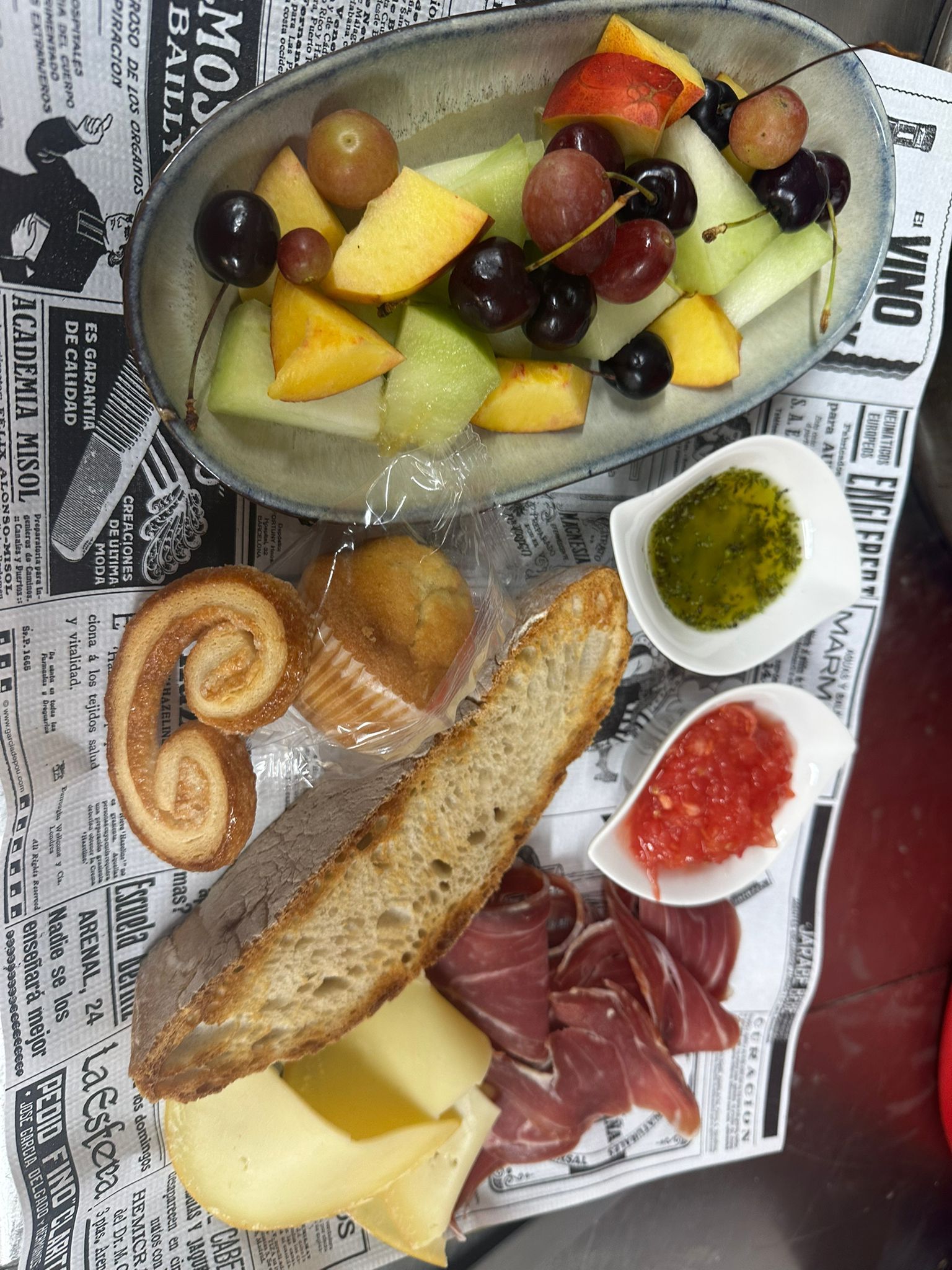 Une assiette remplie d’un assortiment de fruits et de fromages, posée sur un journal.