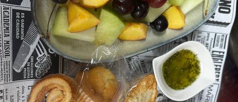 Un plato con frutas variadas y queso sobre un periódico.