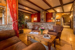 Una habitación acogedora con paredes de piedra, vigas de madera y sillones de cuero.