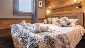 A cozy room with a wooden headboard, a large bed with white linens, and a fluffy rug. - 300m from resort center, swimming pool, sauna, fireplace or stove, tv, ski locker, 97m², Val Thorens (Val Thorens)