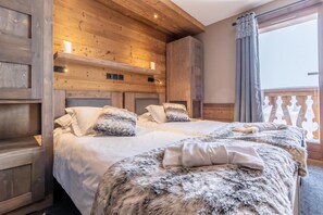 A cozy bedroom with two beds, wooden paneling, and a balcony with a railing. - 300m from resort center, swimming pool, sauna, fireplace or stove, tv, ski locker, 97m², Val Thorens (Val Thorens)