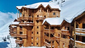 Un chalet en bois à plusieurs étages, doté de balcons et entouré de neige.