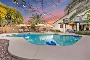 A swimming pool with lounge chairs and umbrellas, surrounded by a landscaped garden and a building with outdoor seating. - Sparkling SaltwtrPool•Spa•Firepit•Netflix•NFL+ (Phoenix)
