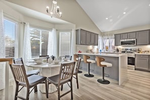 A modern kitchen with a dining area, featuring a central island, bar stools, and a chandelier. - Sparkling SaltwtrPool•Spa•Firepit•Netflix•NFL+ (Phoenix)