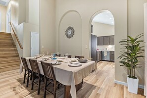 A dining area with a table set for six, wooden chairs, a clock on the wall, and a staircase leading to another level. - Sparkling SaltwtrPool•Spa•Firepit•Netflix•NFL+ (Phoenix)