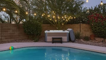 Ein Garten mit Schwimmbad, Whirlpool und Lichterketten.
