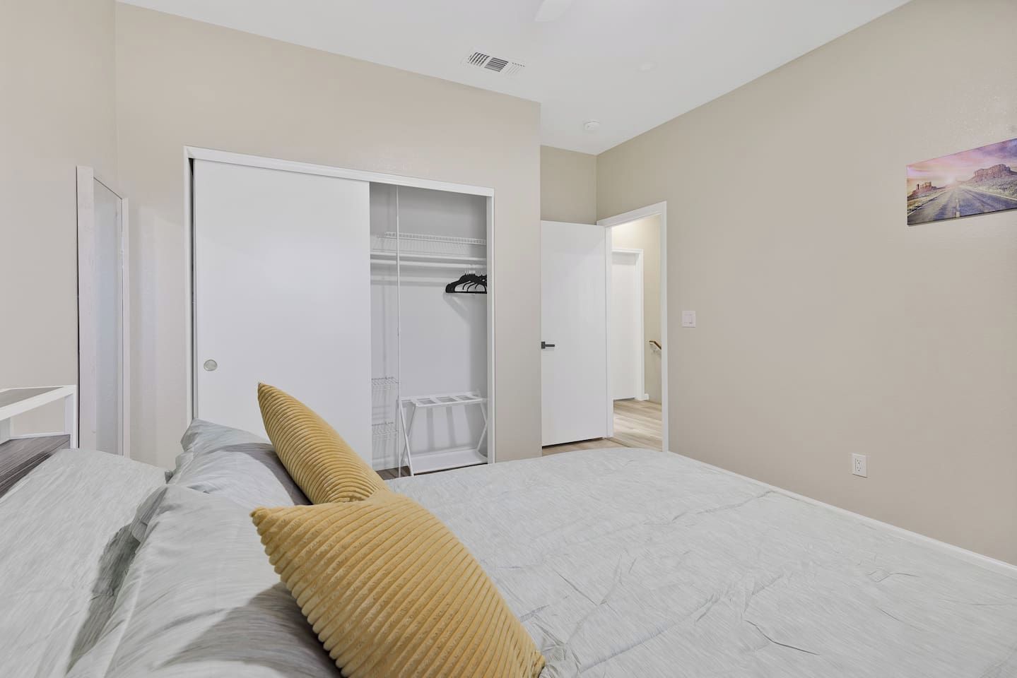 Une chambre à coucher comprenant un lit, une armoire et un couloir menant à une autre pièce.