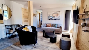 Ein modernes Wohnzimmer mit einem schwarzen Sessel, einem grauen Sofa und einer Wand als Holzdekor.