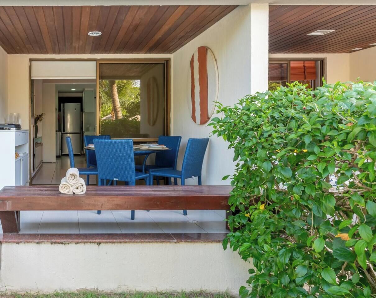 An outdoor seating area with a wooden bench, blue chairs, and a table.