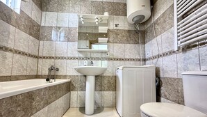 Un baño con bañera, lavabo, inodoro y lavadora incorporada.