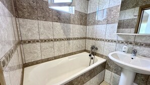 Un baño con bañera, lavamanos y ventana.