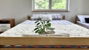 Una cama bien hecha con un edredón estampado y una pequeña planta a un lado.