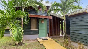 Un bâtiment avec une porte verte, une rampe menant à l’entrée et une petite fenêtre ornée d’une découpe en forme d’animal en bois.