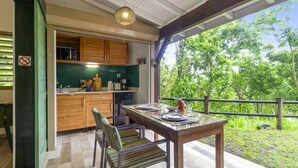 Une cuisine avec des meubles en bois, une table à manger avec des chaises, et une vue sur la verdure à l’extérieur.