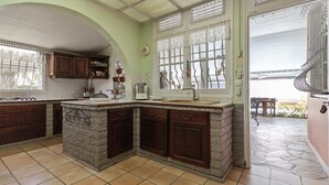 A kitchen with a stone island, wooden cabinets, and a large window with decorative iron bars.