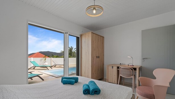 Une chambre avec un lit, un bureau, une chaise et une vue sur une piscine et des montagnes.