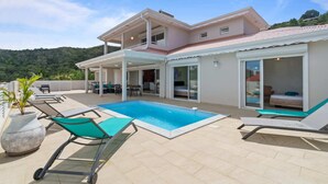 Une maison à deux étages dotée d’une piscine, d’un espace extérieur aménagé et offrant une vue sur les collines environnantes.