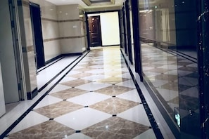 A hallway with a checkered floor pattern, glass doors, and a view into another room. - Fengbo International Apartment (Guangzhou Nansha Wanda Plaza) (Guangzhou)