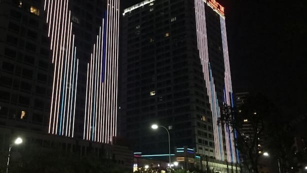Een hoog gebouw met verticale lichtstroken en een opvallend bord.