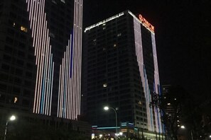 Un edificio de gran altura con tiras verticales de luz y un letrero destacado.