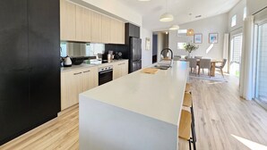 Eine moderne Küche mit einer zentralen Kochinsel, Holzschränken und einem schwarzen Kühlschrank.