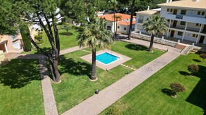 A courtyard with a swimming pool, palm trees, and a building with balconies.