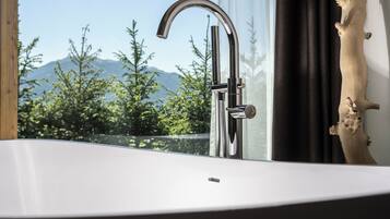 A modern bathroom with a large window, a chrome faucet, and a wooden decor piece.