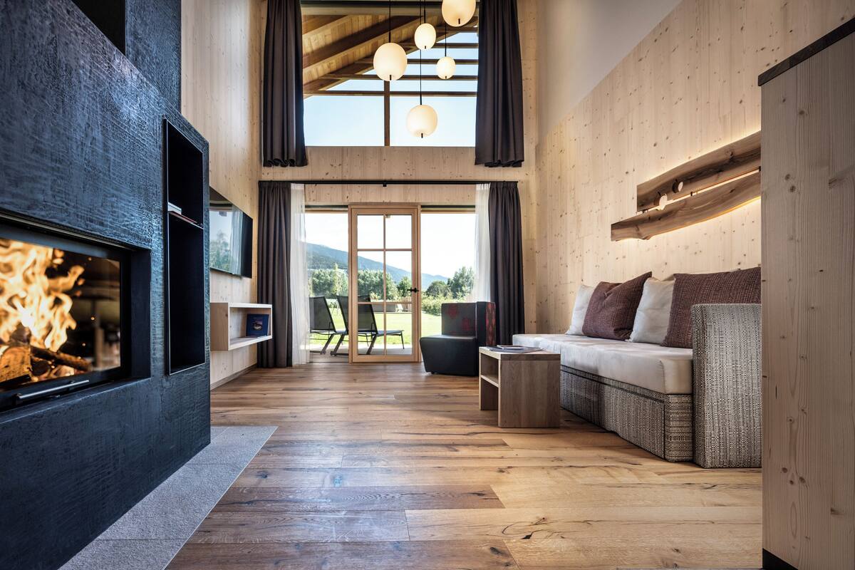 Ein modernes Wohnzimmer mit Kamin, Holzboden und einer Couch.